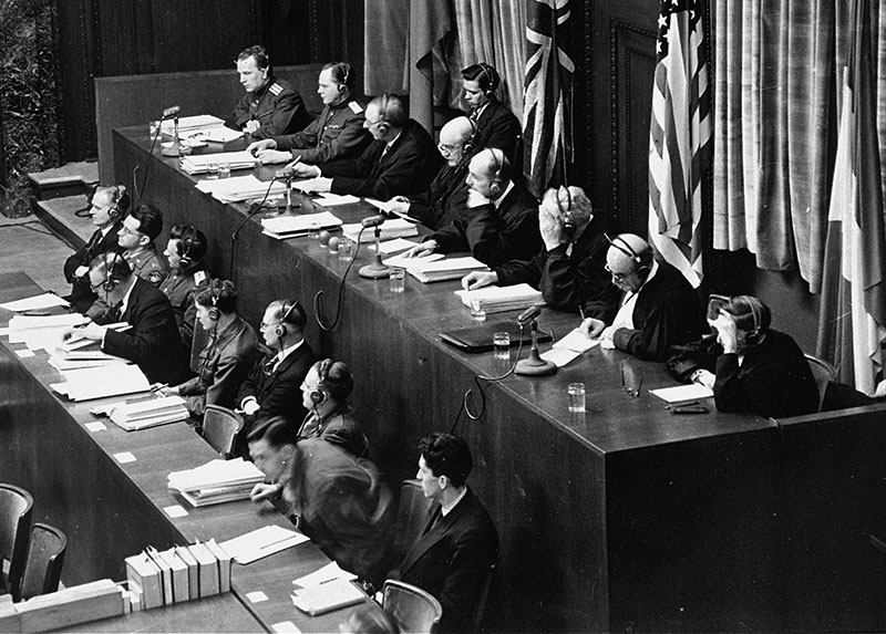 Judges sit at two rows of tables in a courtroom