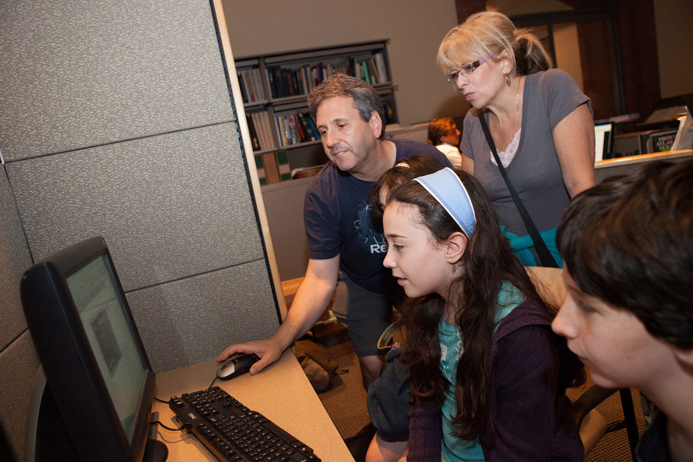 A family sits in front of a computer in the Museum Resource Center.