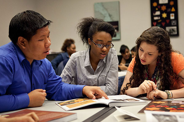 Three students examine documents in a classroom at the Museum