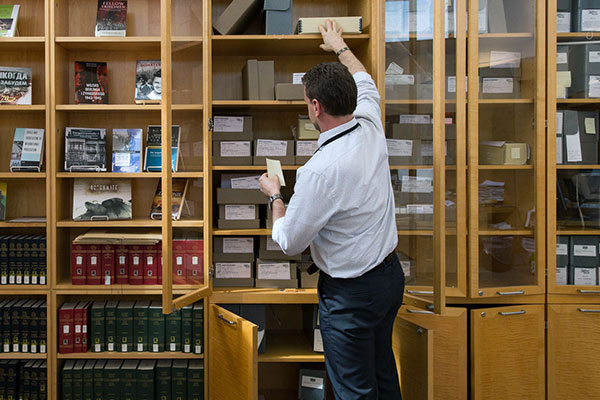 A Museum staff member pulls an item off a shelf in the Library and Reading Room