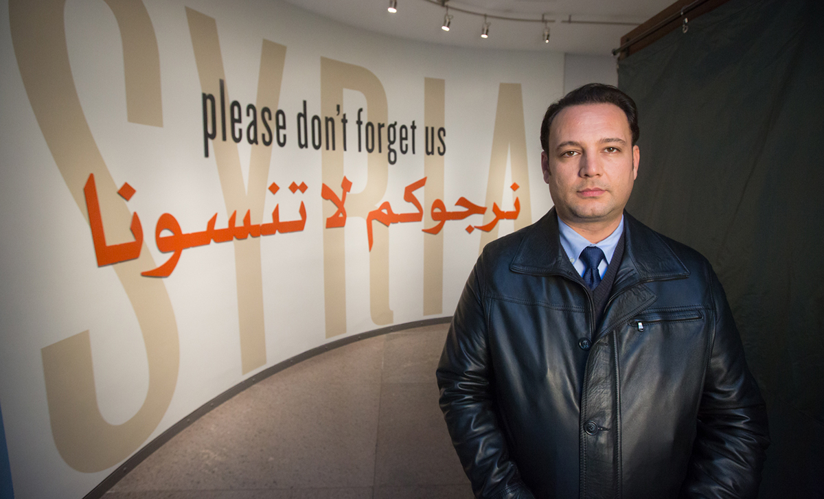 Syrian survivor Mansour Omari stands at the entry of the new exhibition. 