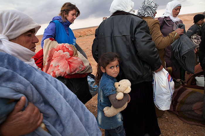 Refugees from the conflict in Syria wait to board a truck to a transit center. The conflict has become the largest humanitarian emergency the world has seen since World War II and international response remains woefully inadequate.