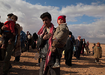 Refugees displaced by the violence in Syria make their way to a transit center in Jordan for trucks that will take them to the Zaatari refugee camp. February 2014.