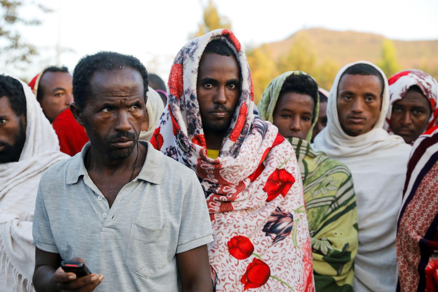 Men stand in line to receive food donations, at the Tsehaye primary school, which was turned into a temporary shelter for people displaced by conflict, in the town of Shire, Tigray region, Ethiopia, March 15, 2021.