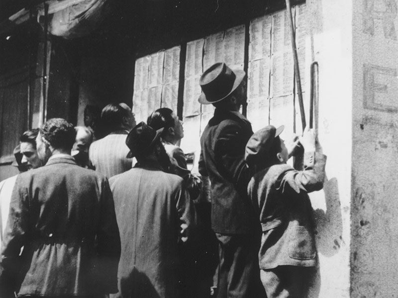 Jewish refugees check the lists of Holocaust survivors that have been posted on the wall of a Jewish-owned bicycle repair shop in Shanghai.