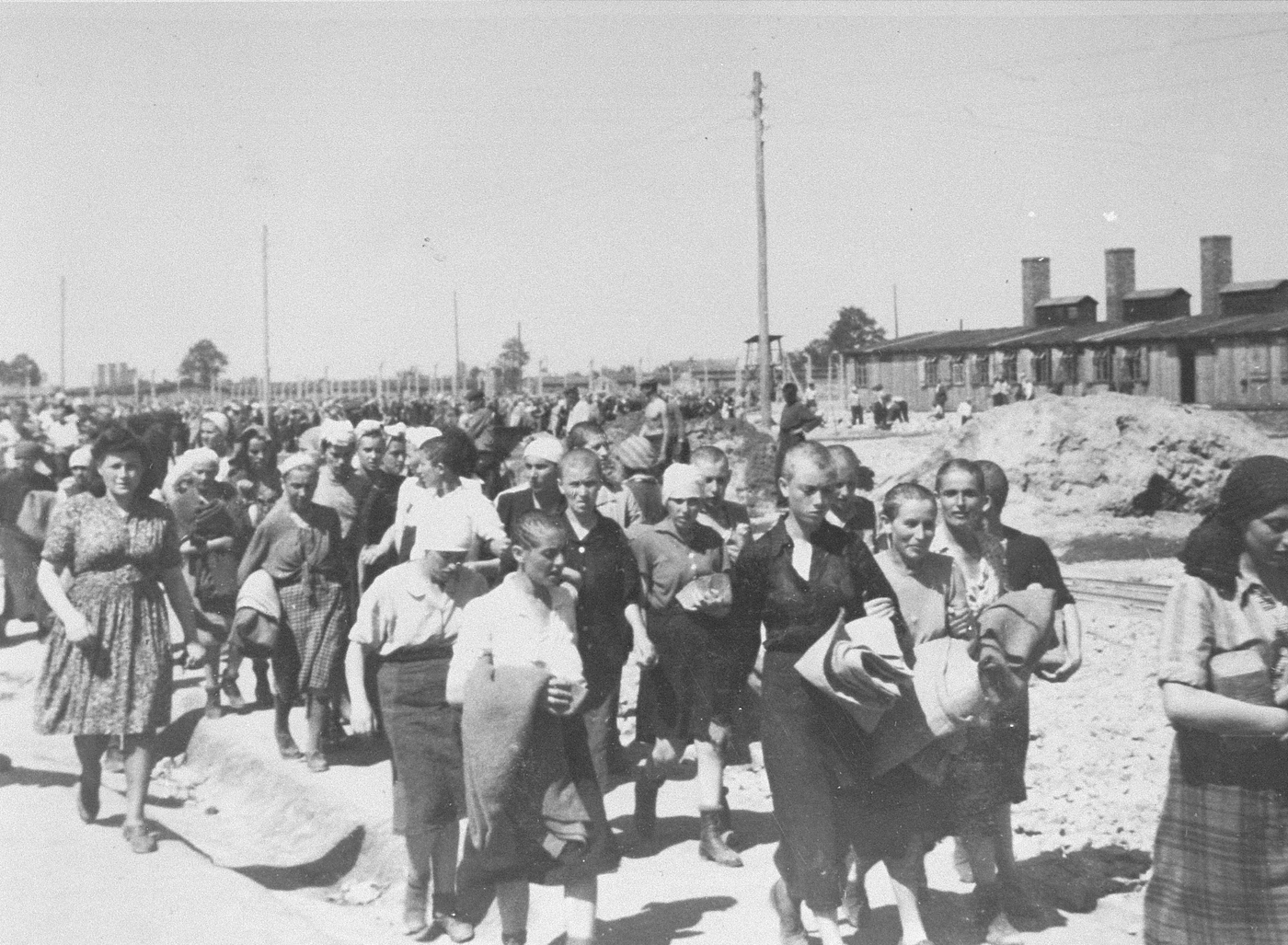 Jewish women from Subcarpathian Rus who have been selected for forced labor at Auschwitz-Birkenau, march toward their barracks after disinfection and headshaving.