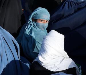 An Afghan girl sits in front of a bakery in the crowd with Afghan women waiting to receive bread in Kabul, Afghanistan, January 31, 2022.