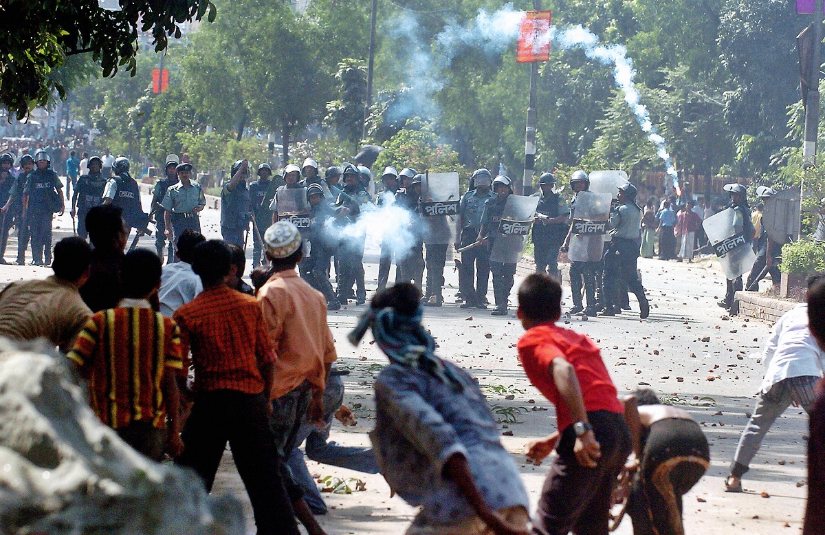 Bangladeshi policemen fire tear gas.