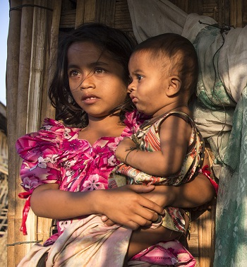 Rohingya children, displaced by violence, wait outside a makeshift shelter in March 2015.