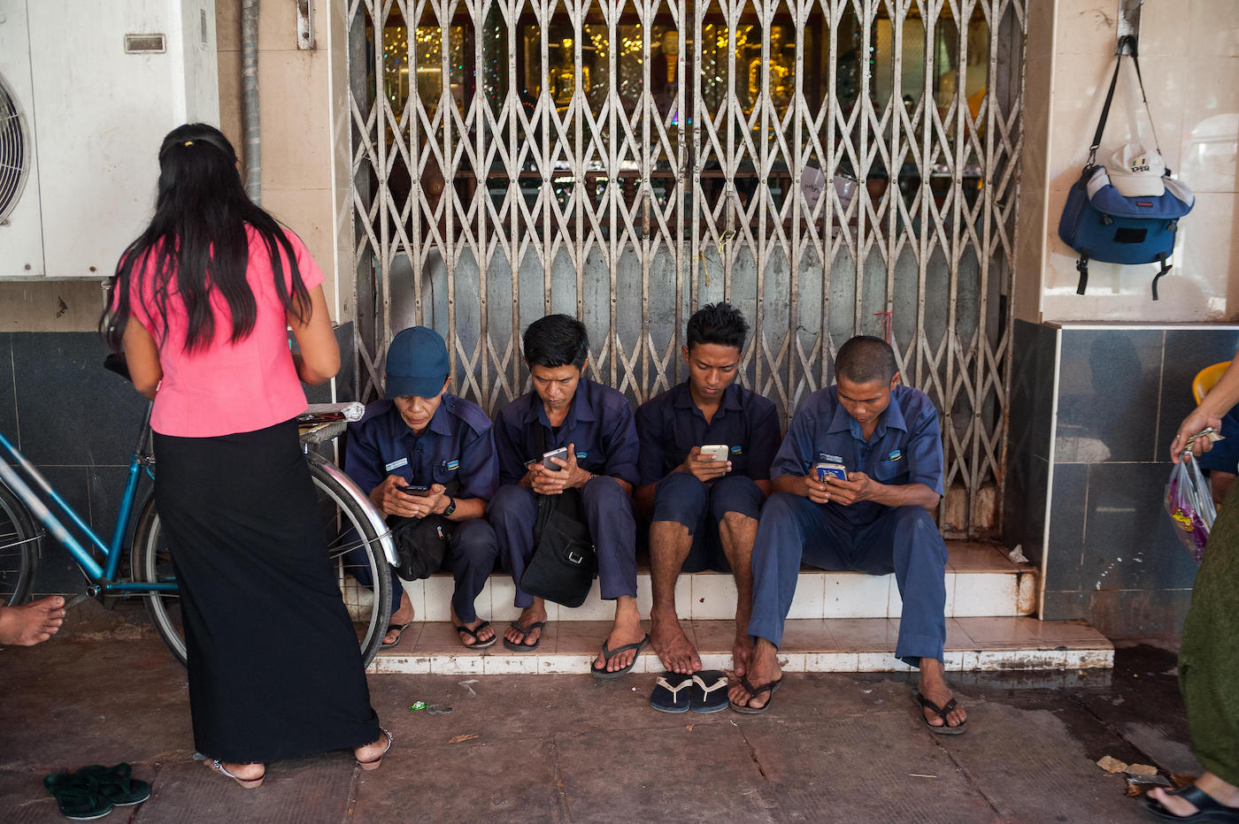 Workers sit in front of a Buddhist temple during their break and use their smartphones. January 27, 2017, Yangon, Republic of the Union of Myanmar, Asia.