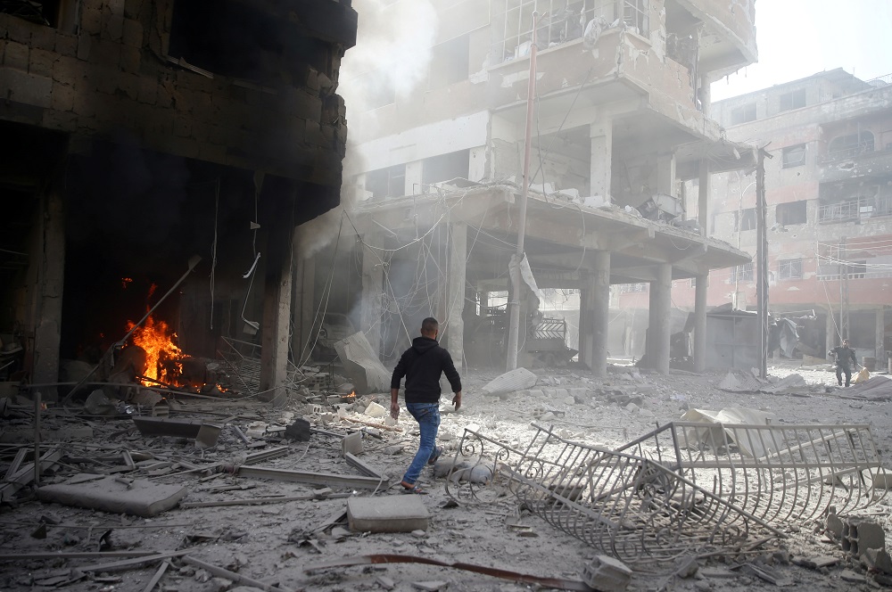 A man walks on rubble at a damaged site after an air strike on February 9, 2018, in the besieged town of Douma in the Eastern Ghouta area of Damascus, Syria.