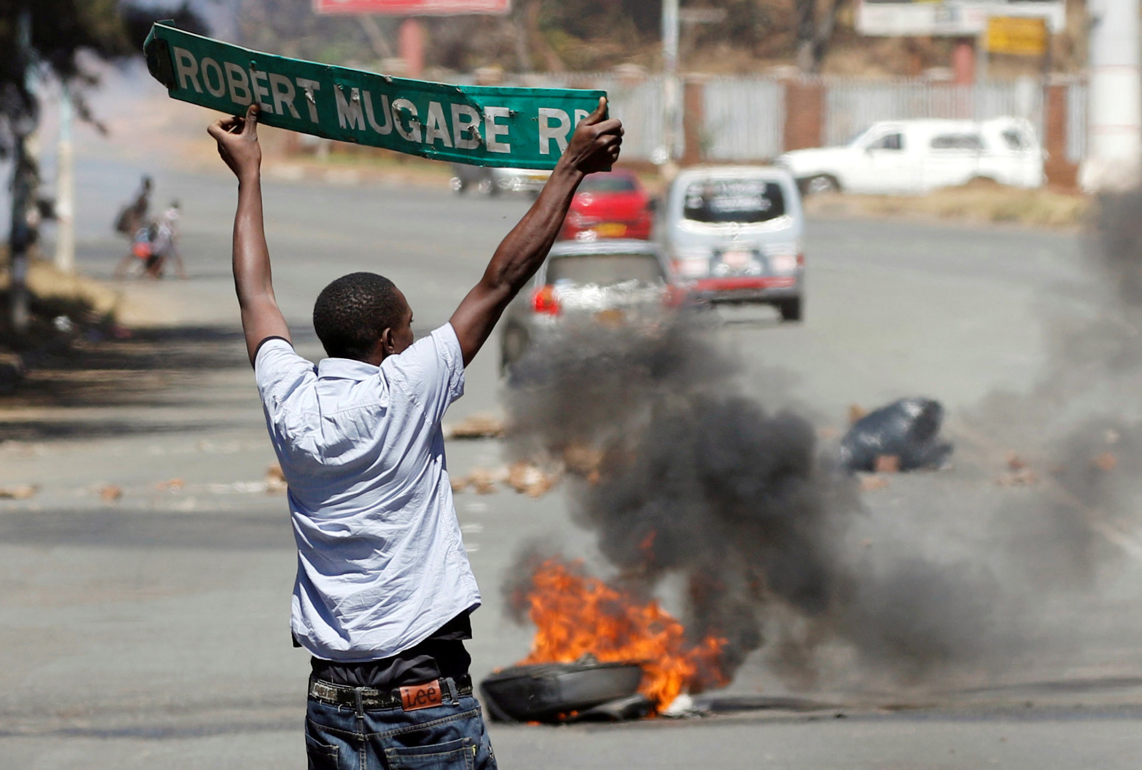 A man carries a street sign as opposition party supporters clash with police in Harare, Zimbabwe, August 26, 2016.