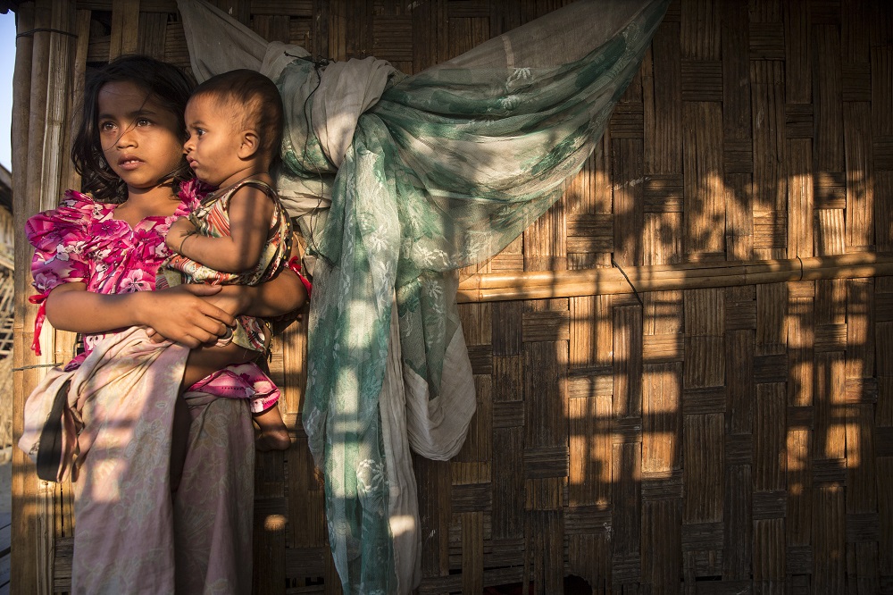 Rohingya children, displaced by violence, wait outside a makeshift shelter in March 2015.